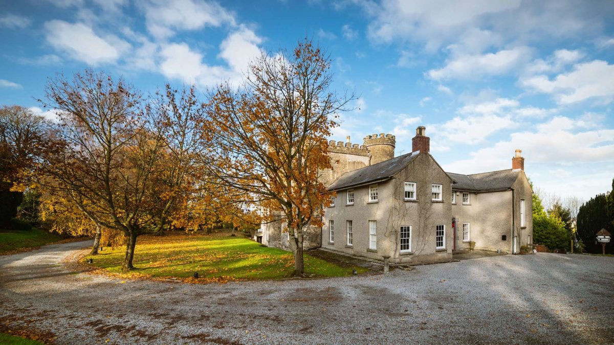 A side view of Smarmore Castle with trees with autumnal coloursed leaves where patients can gor for drug rehab.