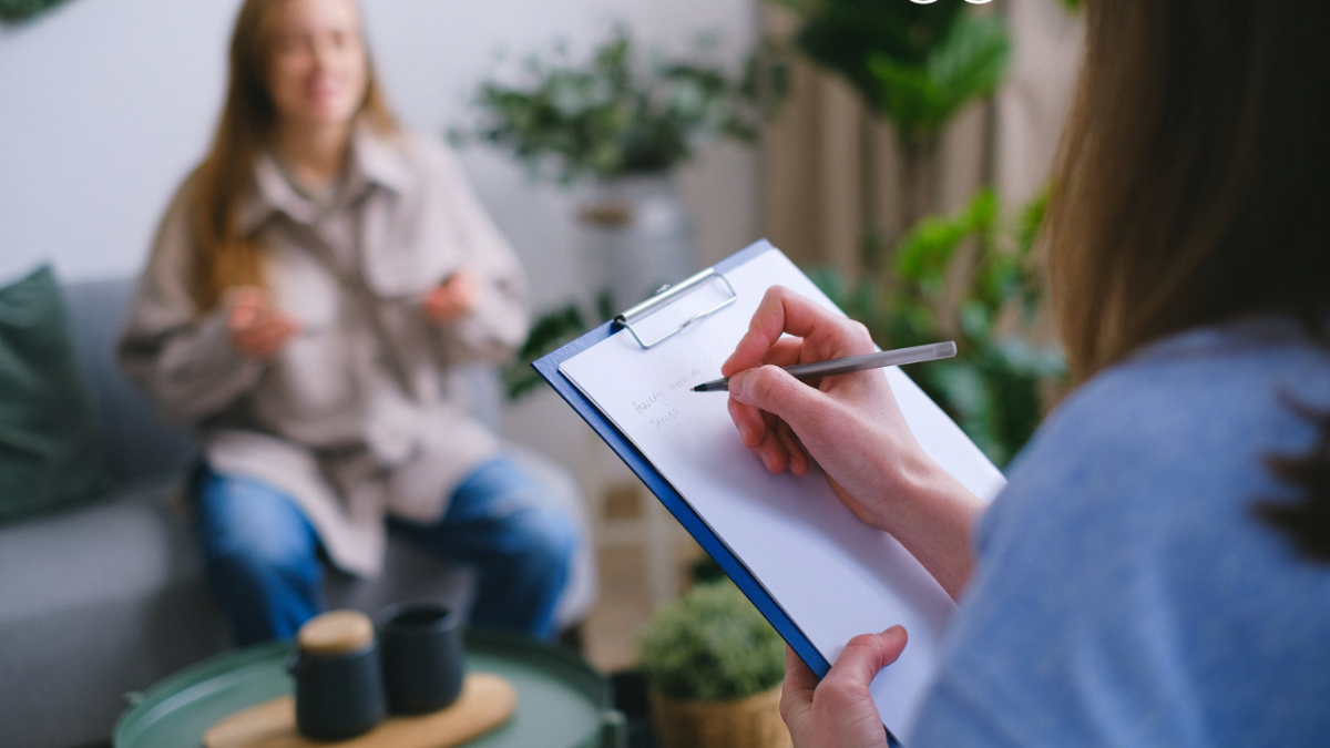A therapist making notes on her clipboard whilst a patient on the sofa opposite discusses her worries regarding cocaine addiction.