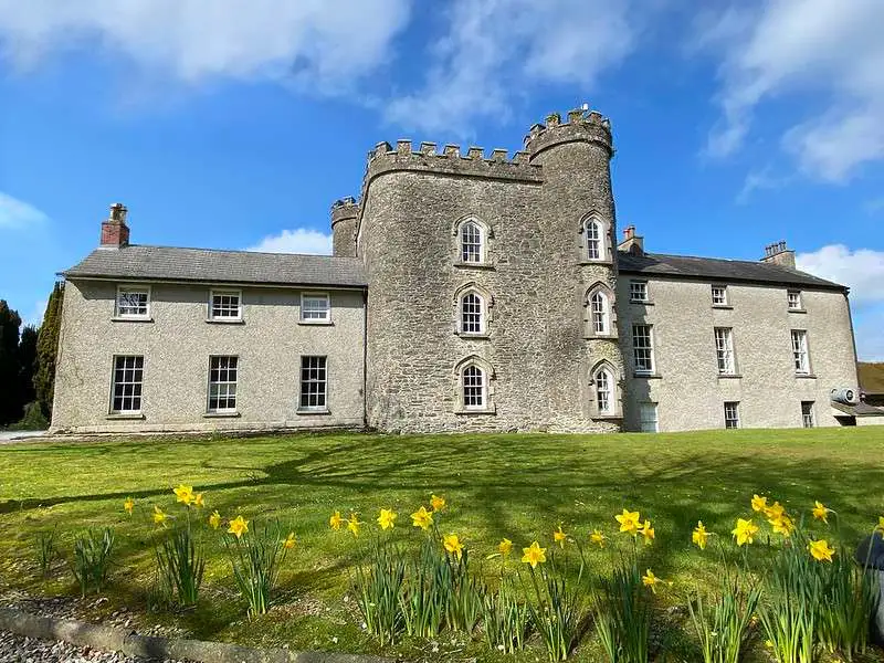 Outdoor photo of Smarmore Castle addiction rehab facility in the sun with daffodils in the foreground