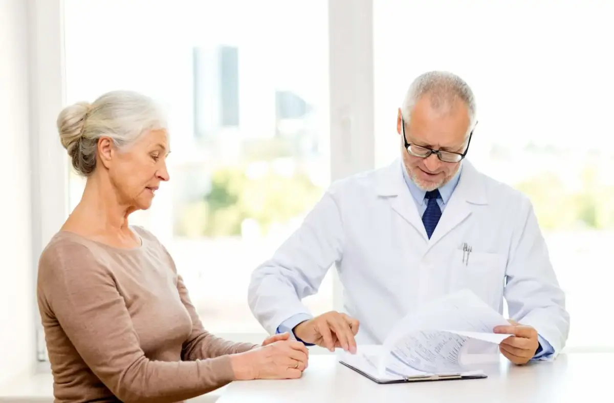 A woman talking with a doctor who is going through paperwork