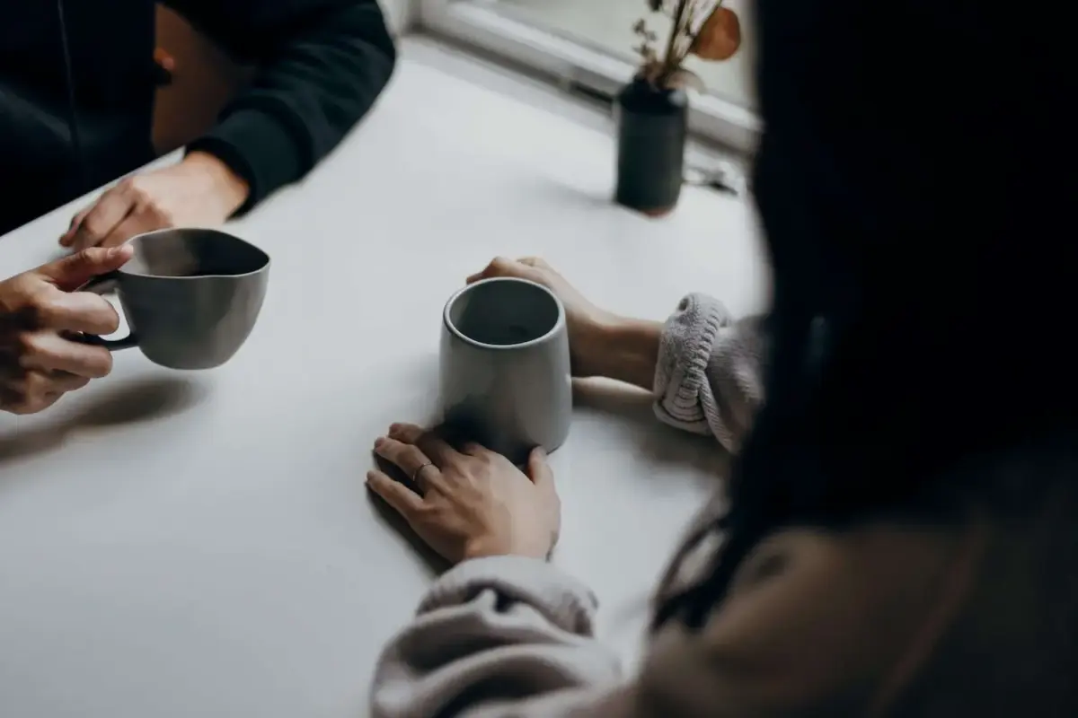 Close up view of two people holding mugs at a table