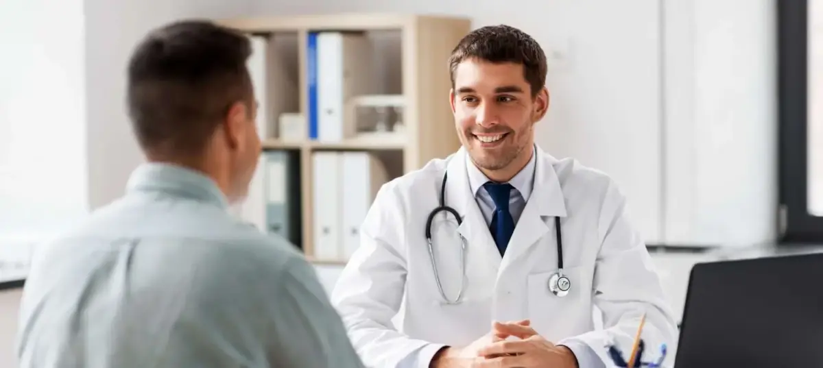 doctor with laptop and male patient discussing treatment