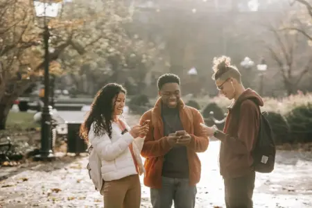 Three friends on phones outside laughing and talking