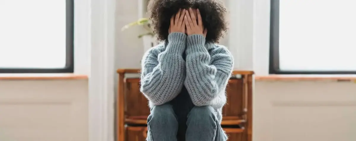 Woman with face obscured by her hands