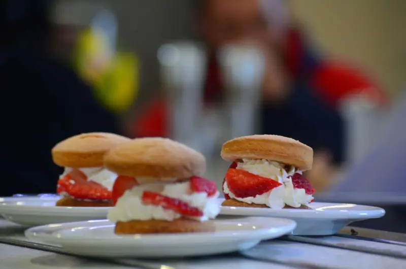 Three plates, each with one scone on them filled with strawberries and cream.