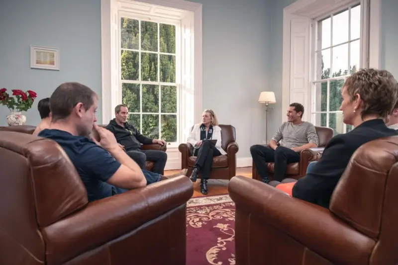 Indoor photo of a group of people sitting in a circle at a 12 step meeting during addiction rehab at Smarmore Castle in Ireland