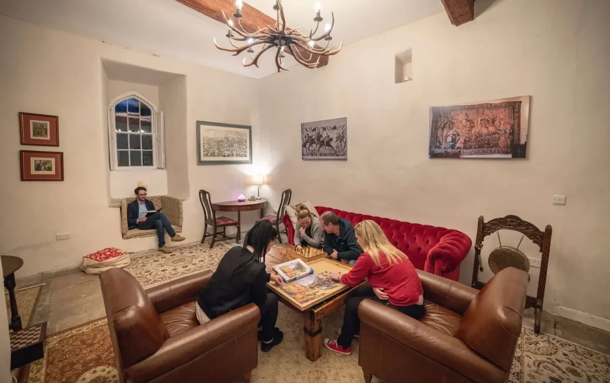group of people sat around a coffee table playing chess and doing a puzzle together at Smarmore Castle