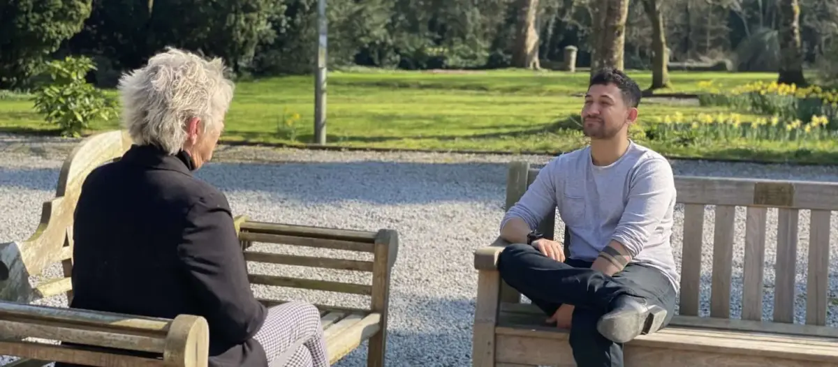 Two people sit on benches across from one another, talking at Smarmore Castle Rehab Clinic in Ireland