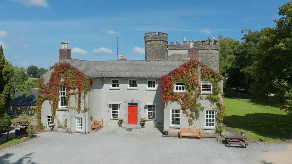 Outdoor shot of Smarmore Castle Private Clinic for addiction treatment, castle is in the sunshine with blue skies behind it and trees around