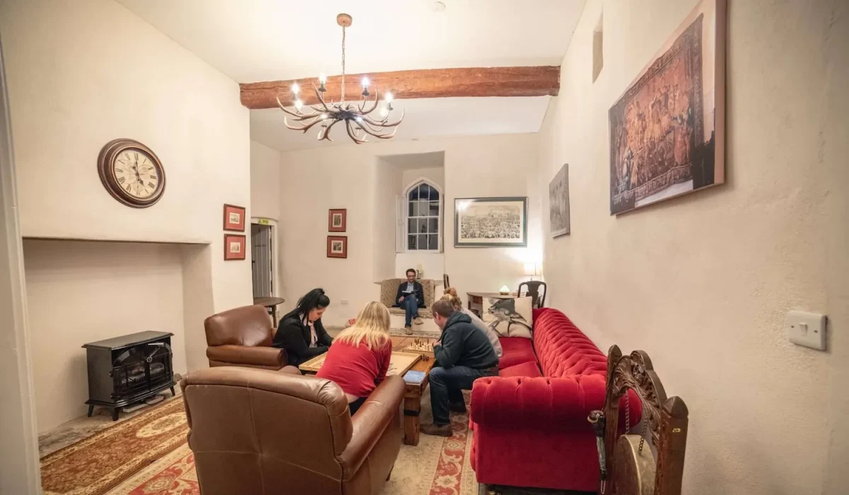 People sitting in armchairs and on a sofa around a coffee table, playing board games at Smarmore Castle while undergoing treatment for addiction