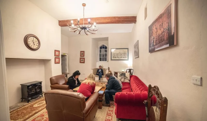 People sitting in armchairs and on a sofa around a coffee table, playing board games at Smarmore Castle while undergoing treatment for addiction