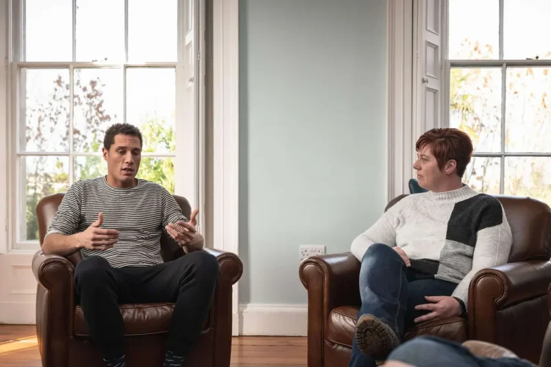 Two people inside at Smarmore Castle sitting in armchairs and talking to each other about addiction