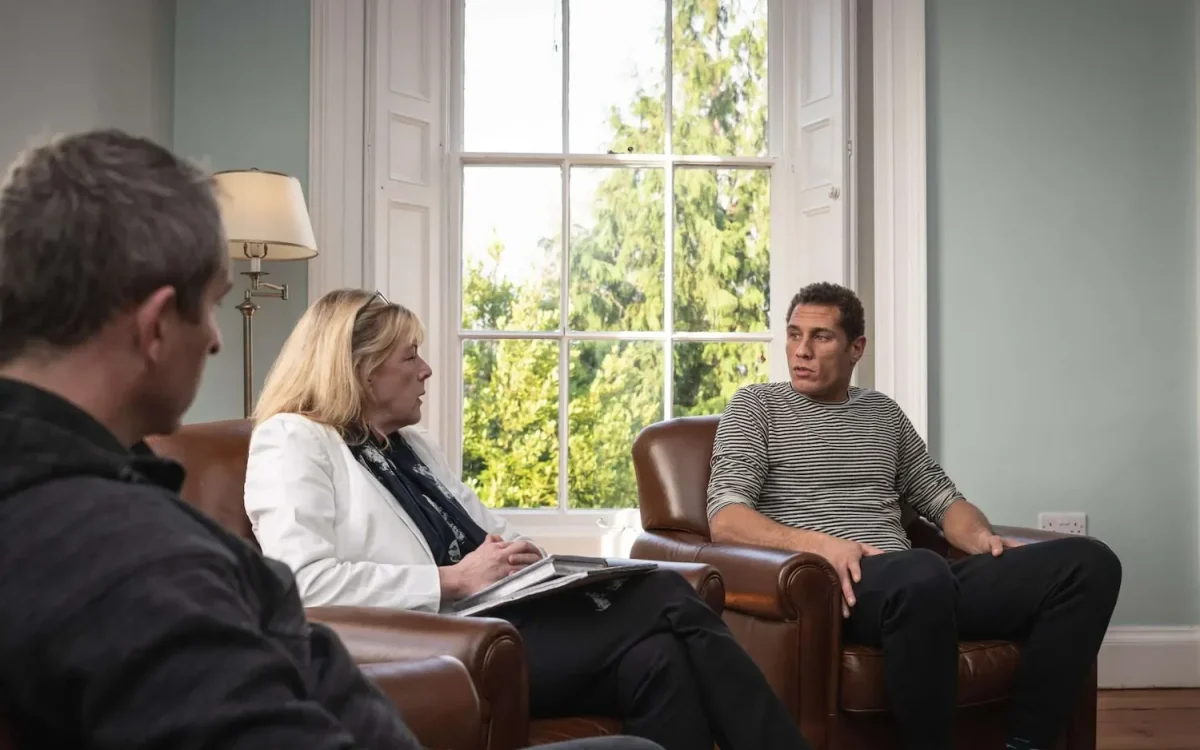 Three people sitting in armchairs talking in a group therapy session at Smarmore Castle