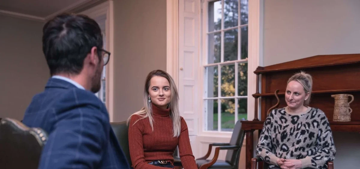 Three people sit in chairs inside talking at Smarmore Castle Private Rehab Clinic