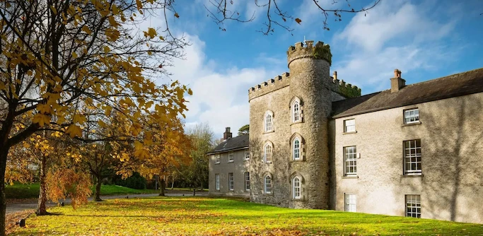 External photo of Smarmore Castle Drug and Alcohol Rehab Clinic in the sun with trees around in autumnal colours