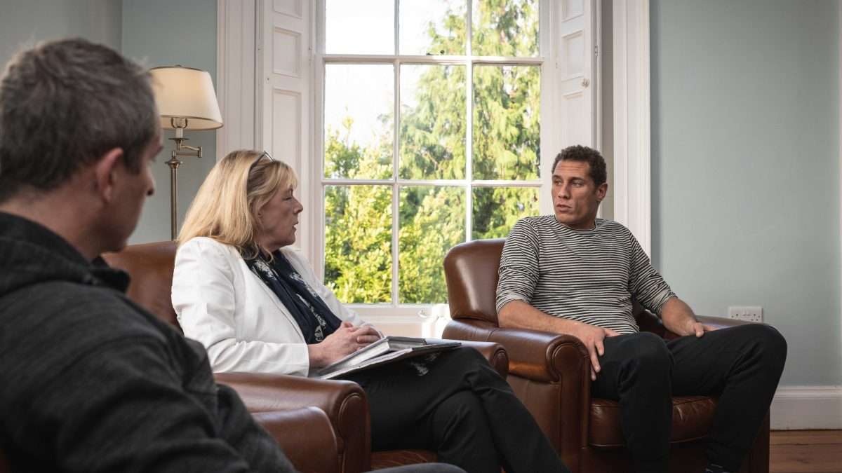 Three people sitting together in therapy for gambling addiction.