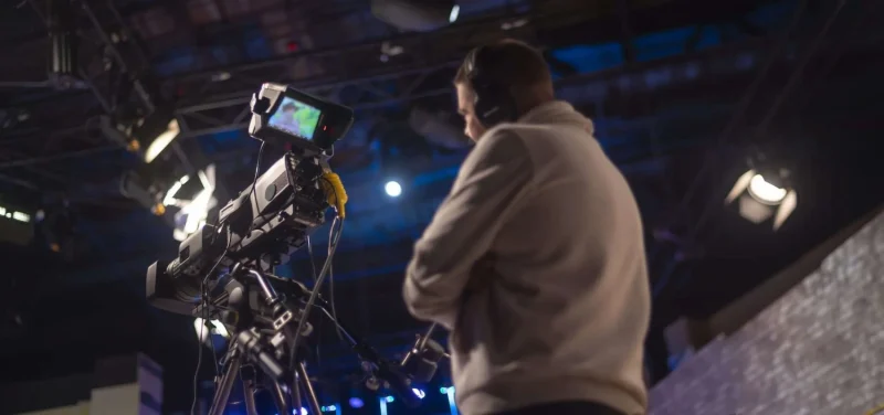 Man standing with staged lighting behind a video camera
