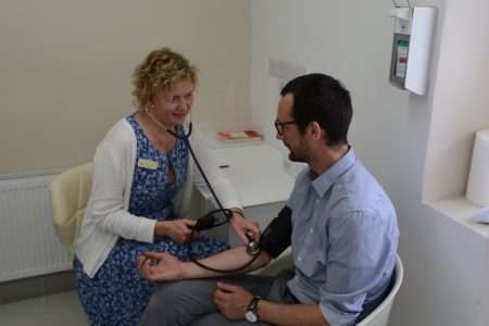 A nurse monitoring a patient's heart rate using a stethoscope whilst discussing the effects of cocaine and alcohol.