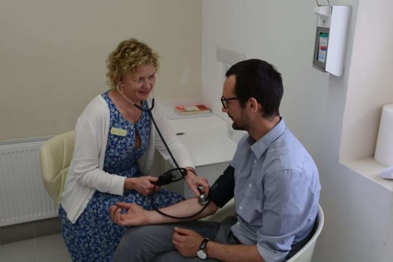 A nurse monitoring a patient's heart rate using a stethoscope whilst discussing the effects of cocaine and alcohol.