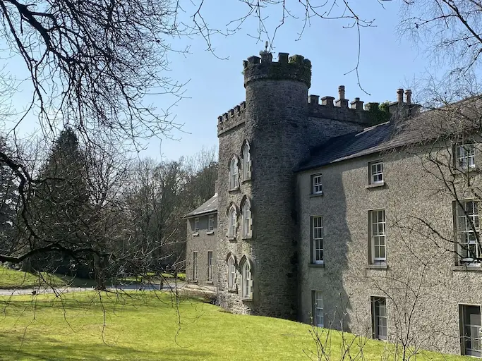 Outdoor view of Smarmore Castle building, sunny day with tree branches framing the castle.