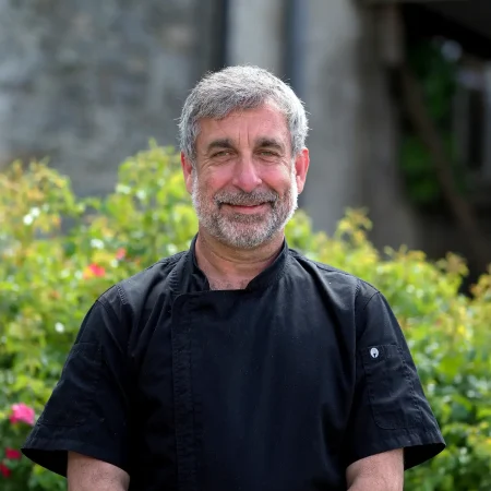 Portrait photo of Dale Collins, Chef of Smarmore Castle, taken outside with green shrubbery in the background