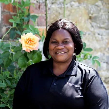 Portrait photo of Francis Asanatu, kitchen assistant at Smarmore Castle, taken outside with a flower in the background