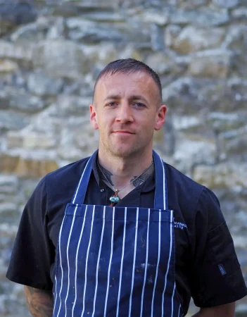 Portrait picture of Tommy Fay, a chef at Smarmore Castle, outside wearing an apron