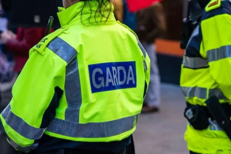 Photo of the back of a fluorescent yellow Garda jacket that reads "Garda"
