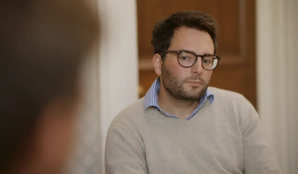 A man wearing a beige jumper talking to a therapist about heroin addiction.